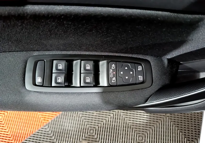 Vue rapprochée des commandes de lève-vitres et réglage des rétroviseurs sur la porte côté gauche d’une Renault Mégane gris clair.