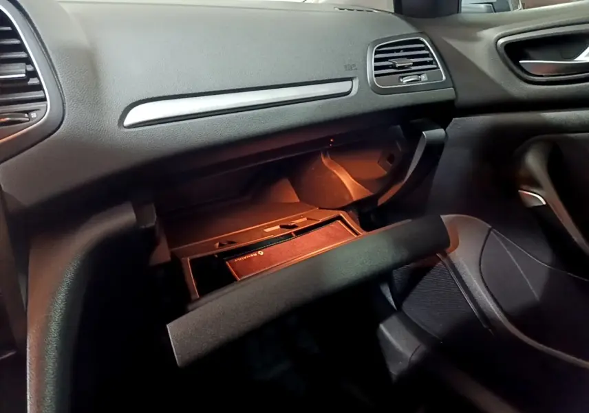 Intérieur Renault Mégane Business Blue dCi 115 2021, vue sur boîte à gants ouverte côté passager avec éclairage orange.
