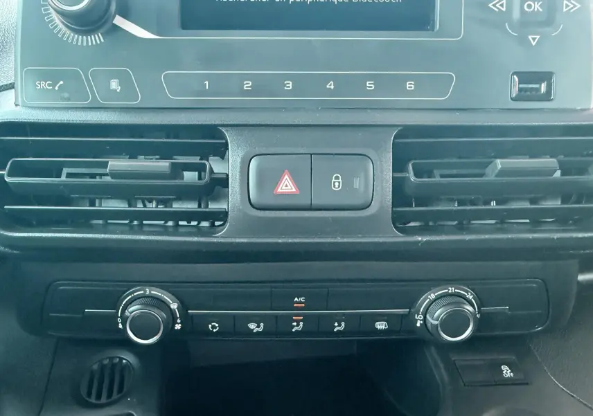 Vue rapprochée du tableau de bord noir du Citroën Berlingo 2019, montrant les commandes de climatisation et l’écran central.