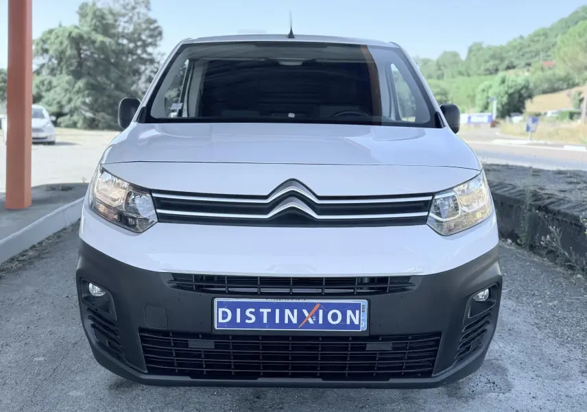 Vue frontale d'un Citroën Berlingo blanc avec calandre noire et plaque d'immatriculation Distinxion visible.