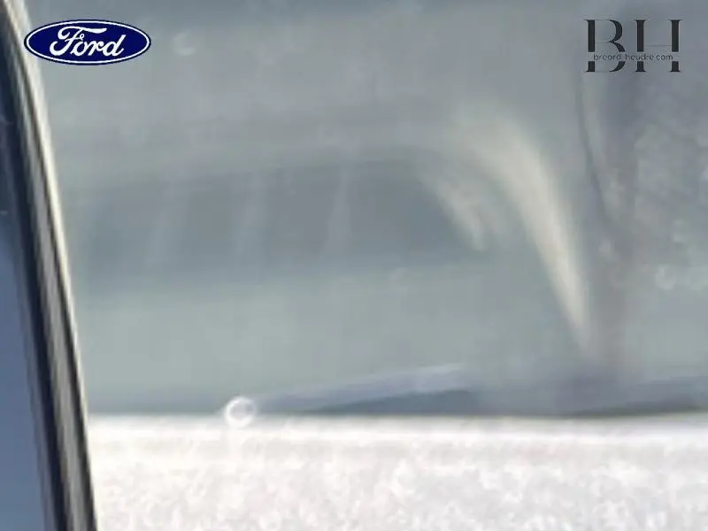 Vue rapprochée sur la vitre latérale gauche d'une Ford Fiesta bleu azur métallisée avec reflet intérieur visible