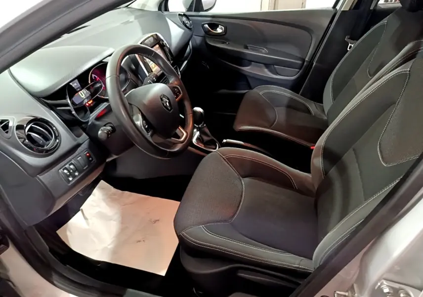 Vue intérieure côté conducteur de la Renault Clio Business 2018, volant cuir multifonctions et sièges tissu noirs.