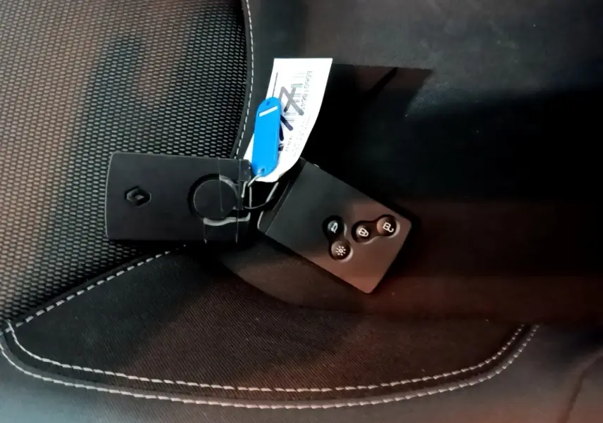 Clé Renault posée sur un siège tissu noir avec surpiqûres blanches, vue rapprochée intérieure sans angle véhicule visible.