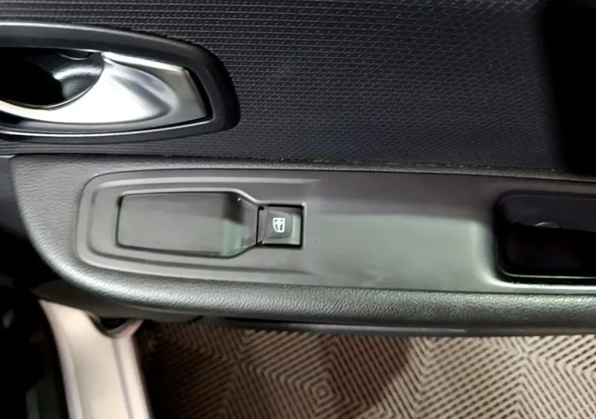 Détail de la commande de lève-vitre côté conducteur sur porte intérieure noire d’une Renault Clio Business gris clair 2018.