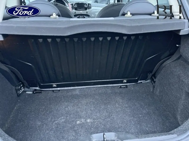 Coffre ouvert vu de l'arrière d'une FIAT 500 Lounge gris métal, avec banquette arrière rabattue et intérieur visible.