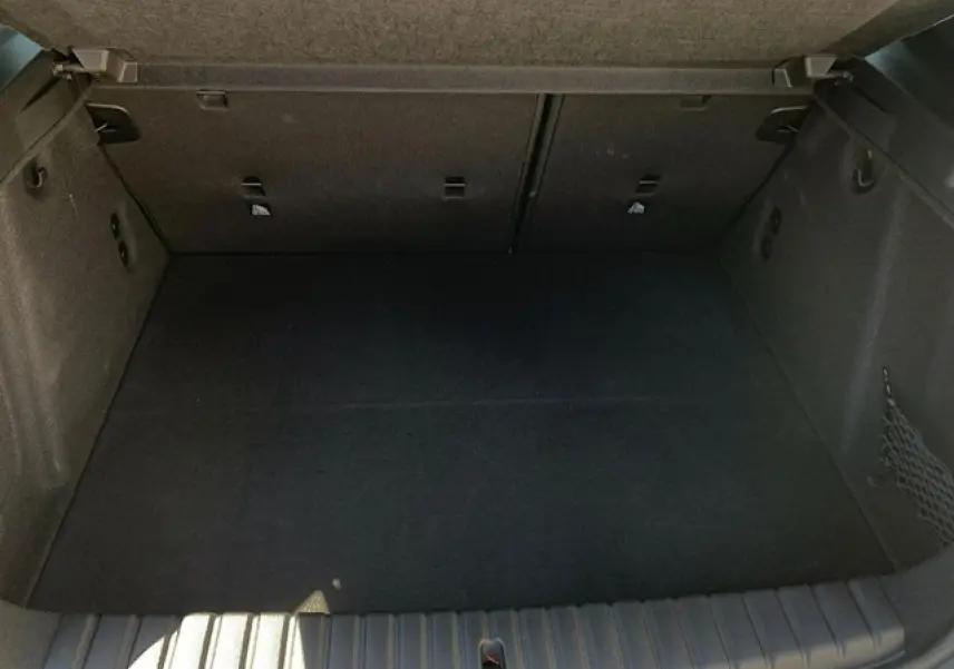 Coffre vide vu de face de la BMW Série 1 118d M Sport noir métal avec filet de rangement côté droit.