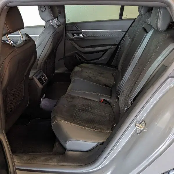 Vue intérieure arrière droite du Peugeot 508 SW gris selenium, montrant les sièges arrière en cuir noir et alcantara avec surpiqûres contrastées.