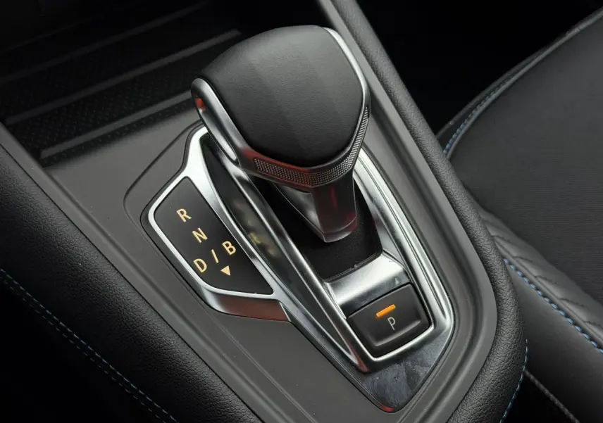 Gros plan sur la commande de boîte automatique du Renault Captur Bleu Iron, avec surpiqûres bleues visibles sur l'accoudoir.