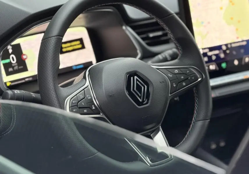 Vue rapprochée du volant noir avec surpiqûres tricolores du Renault Captur 2025, tableau de bord numérique en arrière-plan.