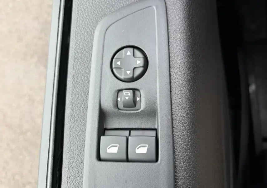 Gros plan sur les commandes de réglage des rétroviseurs et des vitres sur la porte intérieure grise du Peugeot Expert Fourgon blanc.