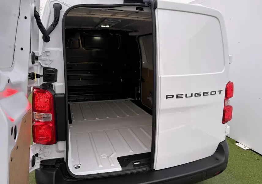 Vue arrière droite d’un Peugeot Expert Fourgon blanc Icy avec portes arrière ouvertes montrant l’espace de chargement éclairé.
