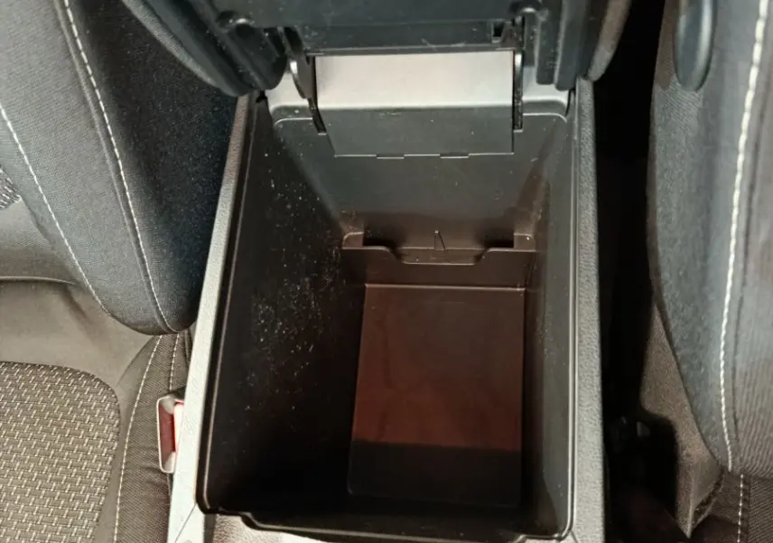 Vue plongeante sur le rangement central ouvert entre les sièges avant noirs du Renault Kadjar Business gris foncé.