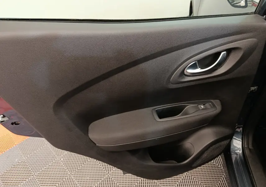 Gros plan sur la porte intérieure côté droit du Renault Kadjar gris foncé, montrant la poignée et les commandes de fenêtre.
