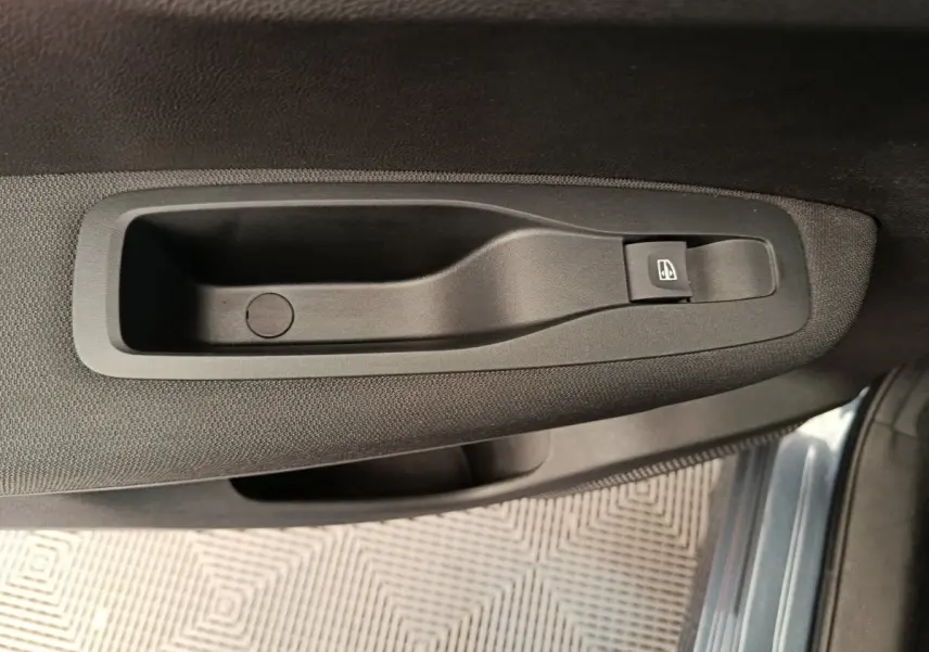 Poignée intérieure de porte côté droit du Renault Kadjar gris foncé 2022 avec bouton de commande de vitre électrique.