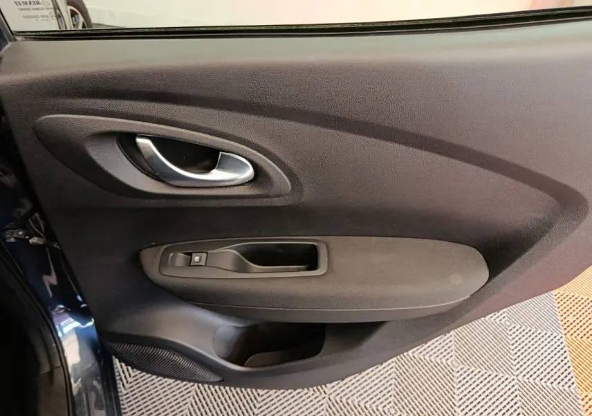 Vue rapprochée de la porte intérieure côté gauche du Renault Kadjar 2022 gris foncé avec poignée argentée et commande de fenêtre.