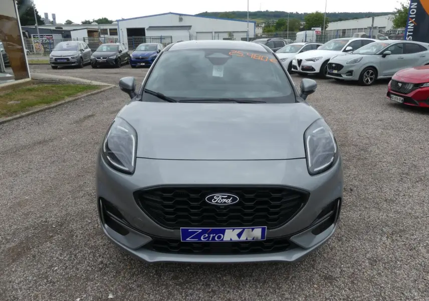 Vue avant d'une Ford Puma 2025 gris métallisé avec calandre noire et phares LED, en extérieur sur parking.