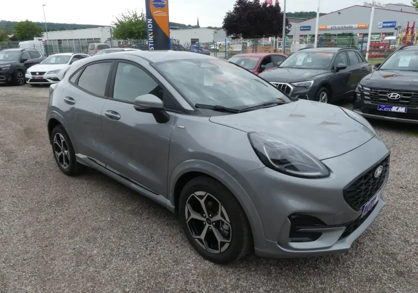 Ford Puma 2025 gris métallisé en vue 3/4 avant droit, avec jantes alliage et calandre noire sportive.
