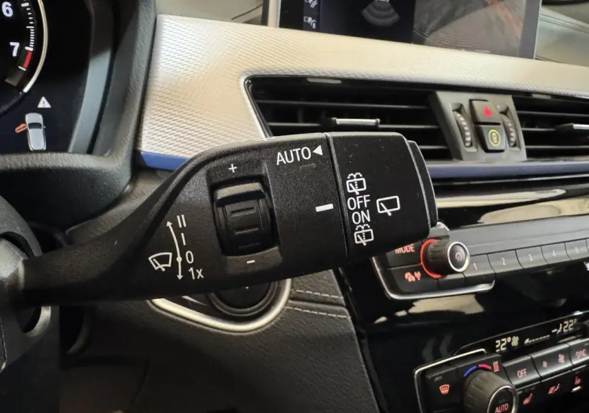 Gros plan sur la commande d’essuie-glace et tableau de bord noir et argenté d’une BMW X2 xDrive25e bleu 2021.