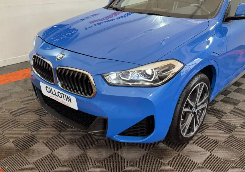 Vue 3/4 avant droite d’une BMW X2 xDrive25e M Sport bleu avec calandre double haricot et phares LED distinctifs.