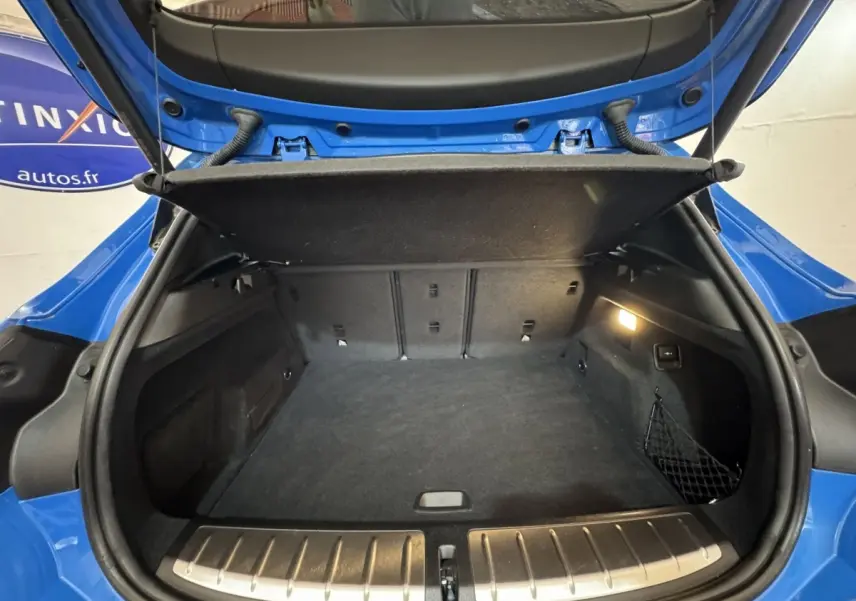Coffre ouvert vu de l'arrière d'un BMW X2 xDrive25e M Sport bleu, avec protection seuil en aluminium visible.