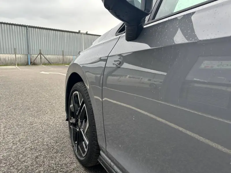 Gros plan sur l’aile avant gauche grise Urano d’une Volkswagen Golf 2.0 TDI R-Line avec logo R et jante alu noire.