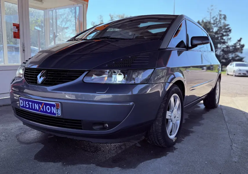 Renault Avantime gris en 3/4 avant droit, mettant en valeur sa silhouette unique et ses phares allumés.
