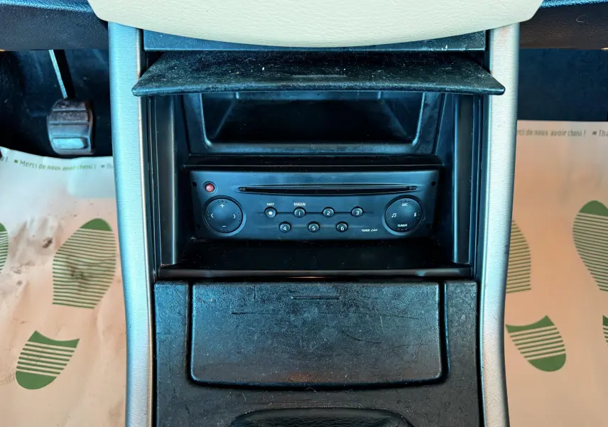 Gros plan sur la console centrale noire du Renault Avantime gris, avec lecteur radio et rangement ouvert.