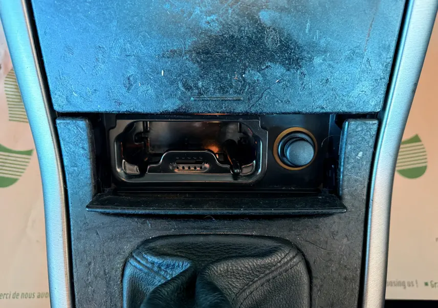 Gros plan sur la console centrale du Renault Avantime gris, montrant un cendrier ouvert et un allume-cigare.