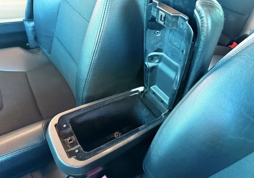 Gros plan sur la console centrale ouverte entre les sièges avant en cuir noir du Renault Avantime gris de 2002.