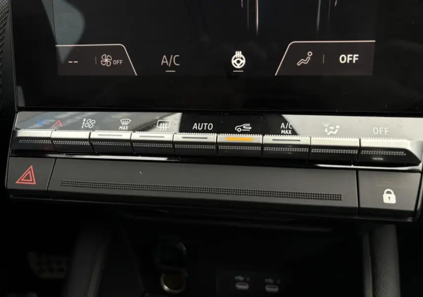 Gros plan sur la console centrale du Renault Captur 2025, boutons de climatisation et écran tactile noir.