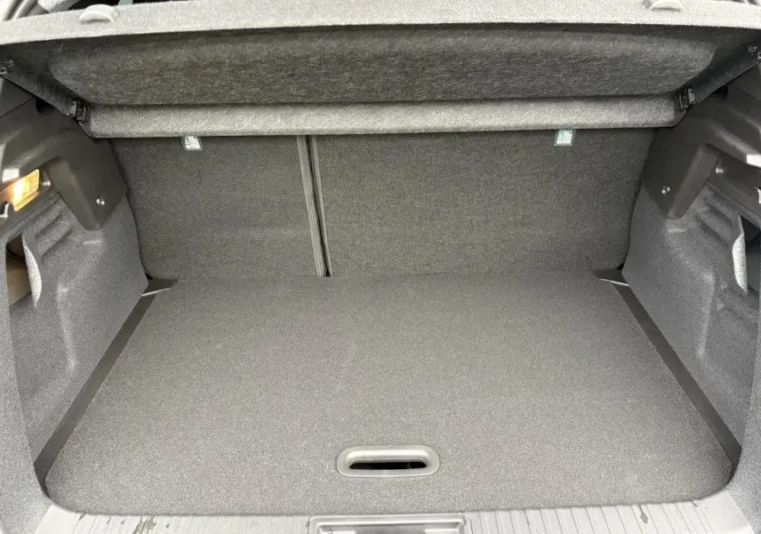 Coffre ouvert du Renault Captur 2025 hybride, vue intérieure montrant le plancher plat et la moquette grise.