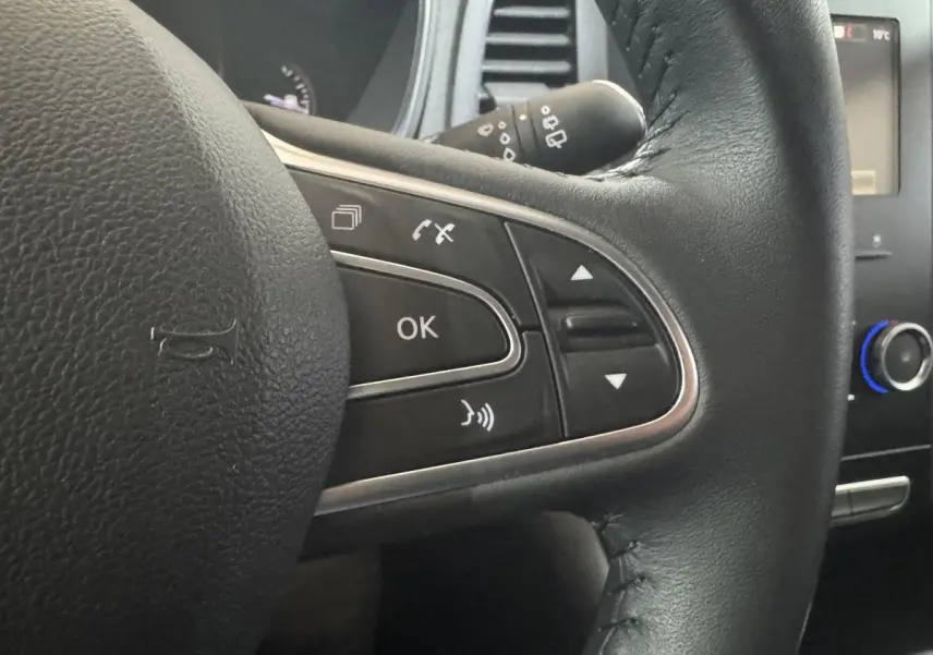 Gros plan sur le volant cuir noir de la Renault Mégane Business, avec commandes multifonctions visibles à droite.