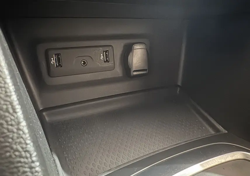 Gros plan sur la console centrale intérieure de la Renault Mégane Business gris clair, montrant prises USB et prise 12V.