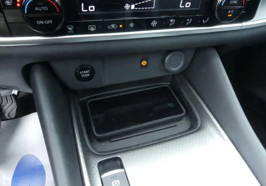 Vue rapprochée de la console centrale du Nissan Qashqai 2025, avec chargeur à induction et commandes climatisation.