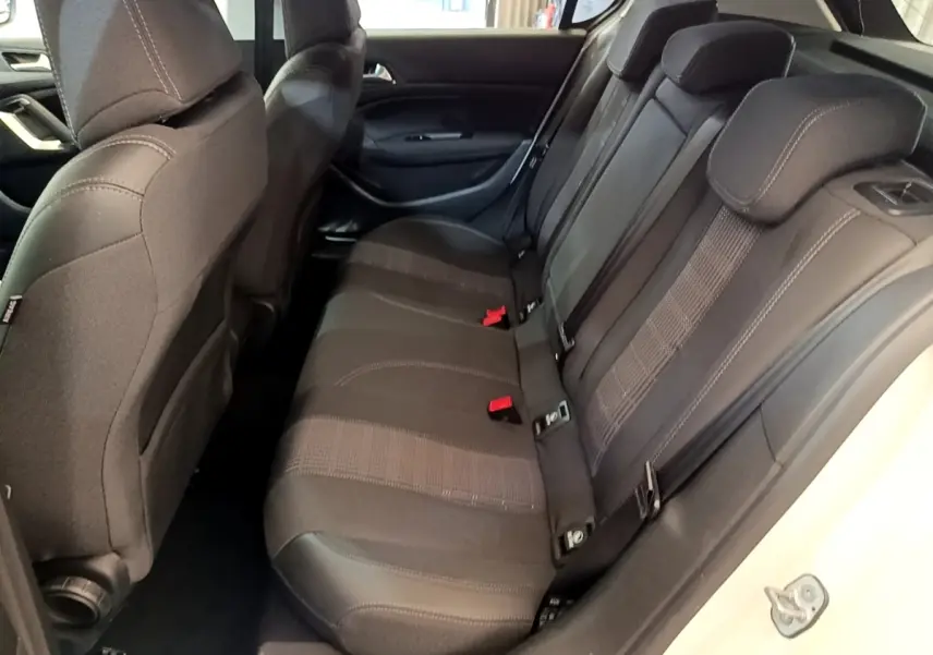 Vue intérieure côté droit sur la banquette arrière noire de la Peugeot 308 blanche, avec appuie-têtes et ceintures visibles.