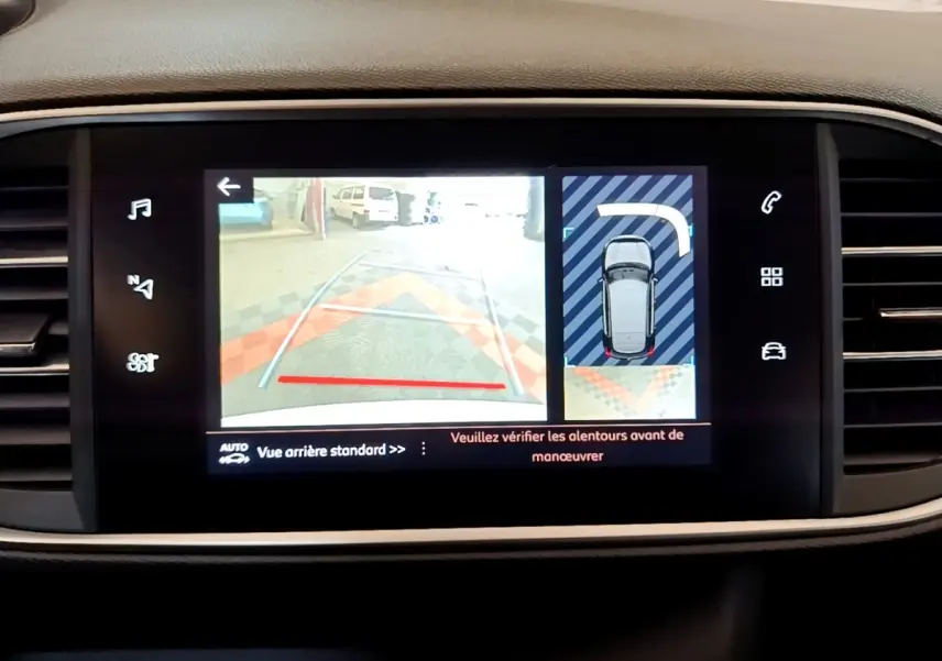 Écran tactile central de la Peugeot 308 blanc montrant la caméra de recul et l’aide au stationnement arrière.