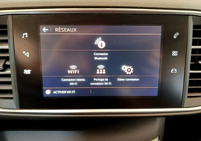 Écran tactile central affichant les options réseau Bluetooth et Wi-Fi dans l'habitacle d'une Peugeot 308 blanche.