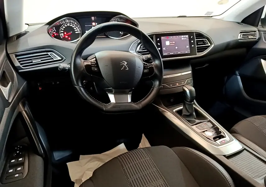 Vue intérieure avant de la Peugeot 308 2017, tableau de bord noir avec écran tactile et volant cuir multifonctions.