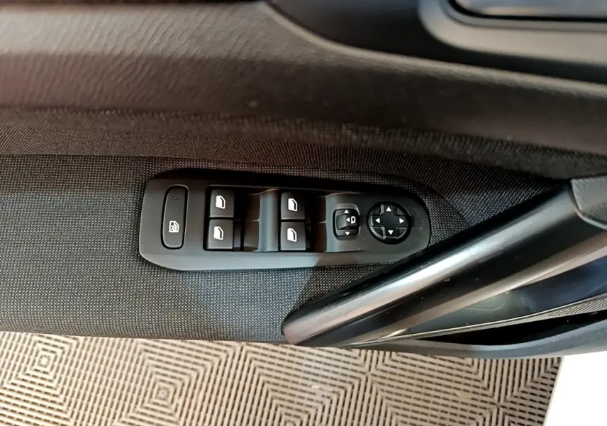 Gros plan sur les commandes des vitres et rétroviseurs côté conducteur d'une Peugeot 308 blanche de 2017.