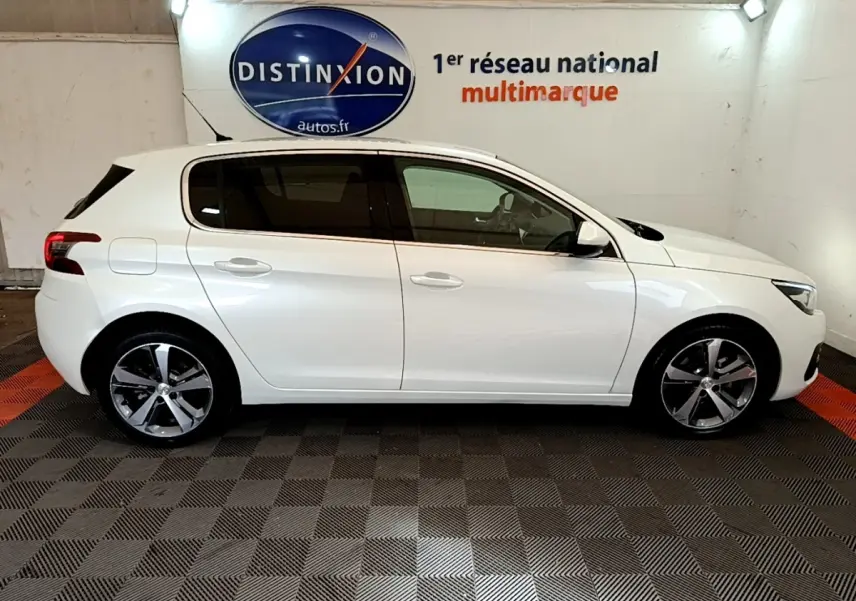 Profil droit d'une Peugeot 308 blanche 2017 dans un showroom avec sol damier et logo Distinxion en arrière-plan.