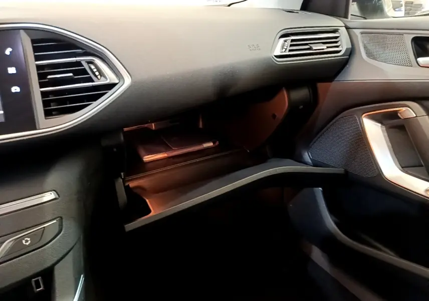 Intérieur de la Peugeot 308 blanc, vue côté passager avec boîte à gants ouverte et tableau de bord noir.