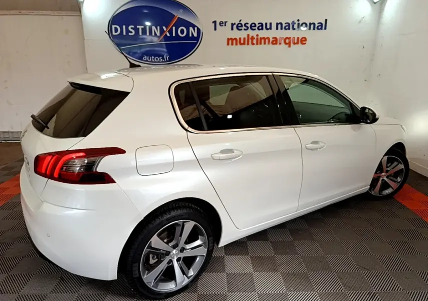 Peugeot 308 blanc vue 3/4 arrière droit, feux arrière LED et jantes alliage visibles en intérieur showroom.