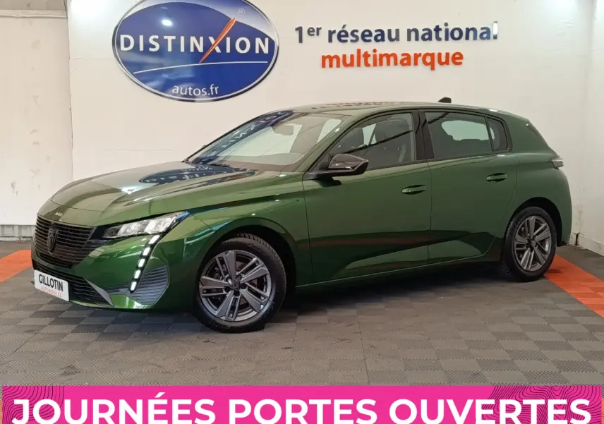 Peugeot 308 vert vue 3/4 avant droit, avec feux LED verticaux et jantes alliage, en intérieur showroom.