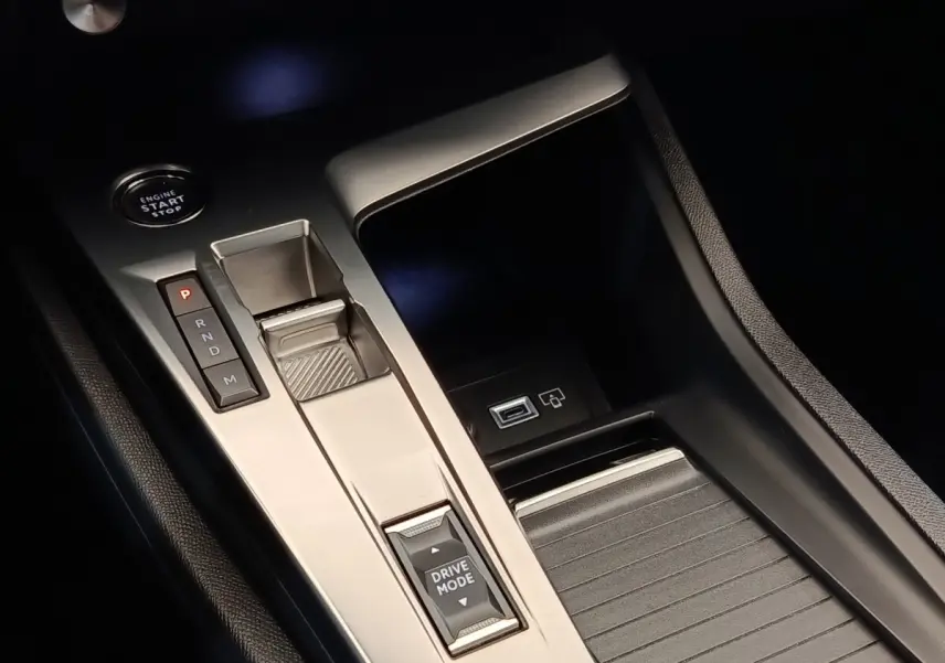 Gros plan sur la console centrale noire et argentée de la Peugeot 308 2023 avec bouton start, sélecteur de vitesses et commande Drive Mode.