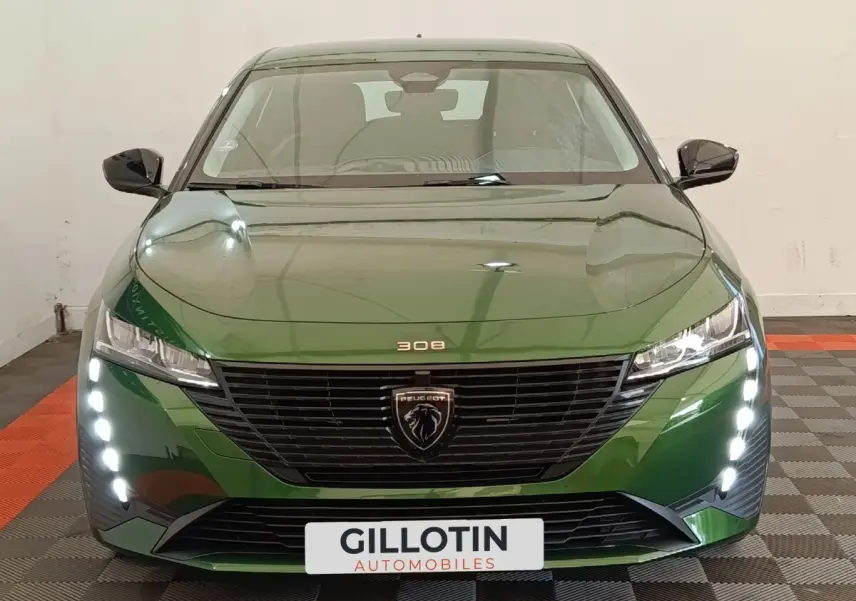 Vue avant d'une Peugeot 308 2023 vert métallisé avec feux diurnes LED verticaux et calandre noire distinctive.