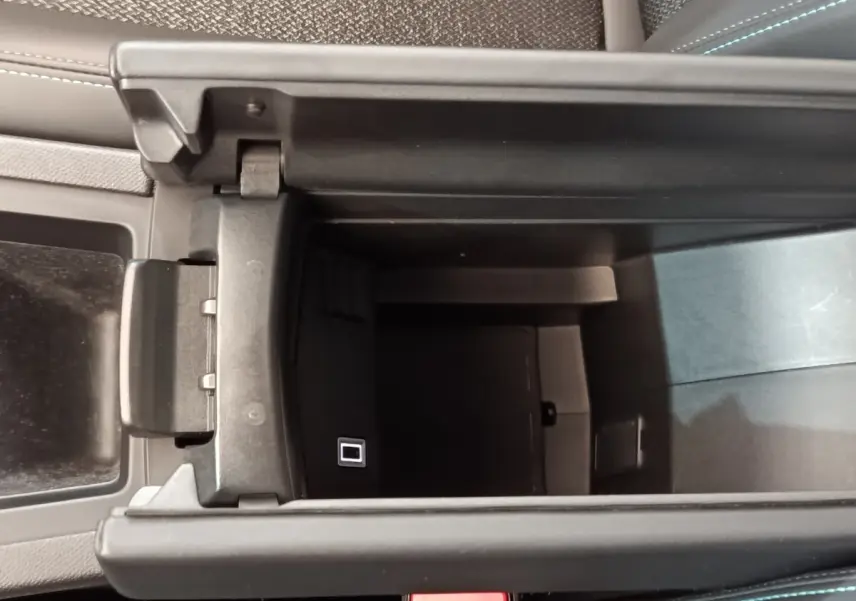 Vue plongeante sur le rangement central ouvert de la Peugeot 308, intérieur noir avec port USB visible.