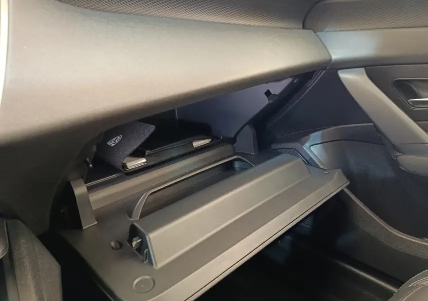 Vue intérieure côté passager de la boîte à gants ouverte dans une Peugeot 308 vert, avec pochette de documents visible.