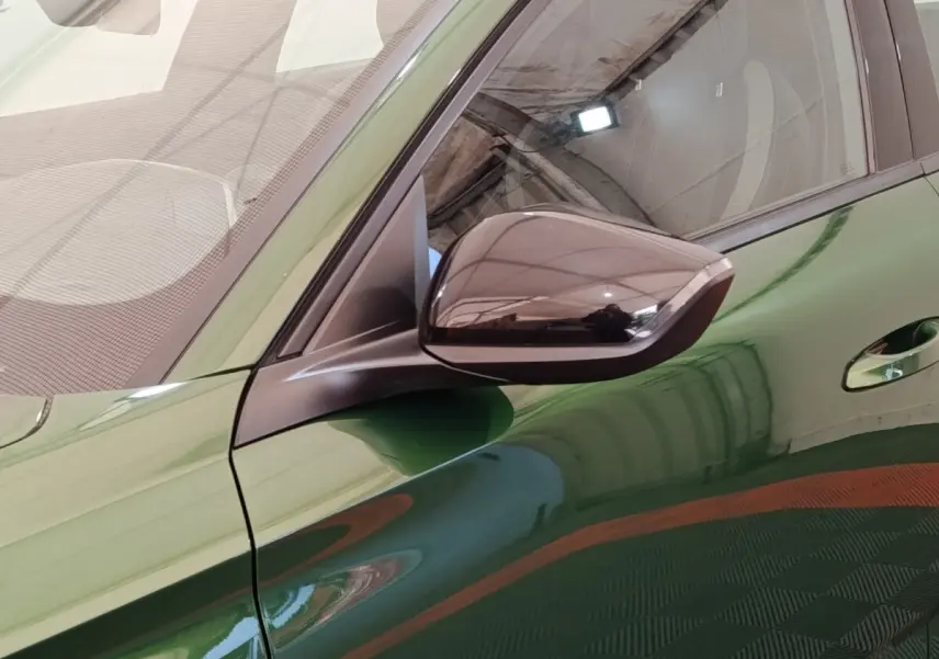 Gros plan sur le rétroviseur droit noir brillant et la portière verte d'une Peugeot 308 2023 vue côté droit.