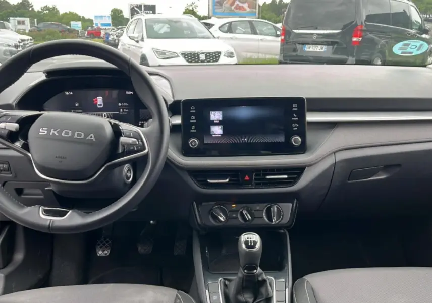 Vue intérieure frontale du tableau de bord et volant cuir noir de la Skoda Fabia 2025 avec écran tactile et boîte manuelle.