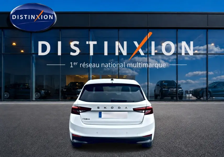 Vue arrière d'une Skoda Fabia blanche 2025 garée devant une vitrine avec logo Distinxion.